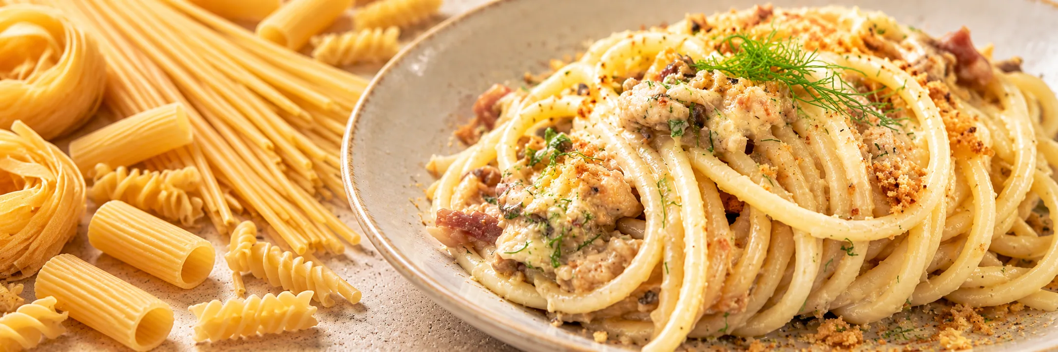 Piatto di pasta con diversi formati di pasta secca sullo sfondo